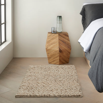 Beige shag rug on light wood floor in a simple bedroom scene.