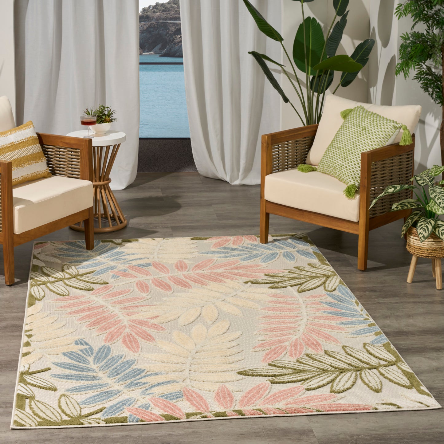 Rectangular area rug with pastel pink, blue, and green palm leaves on beige; boho coastal living room with wicker chairs and greenery.