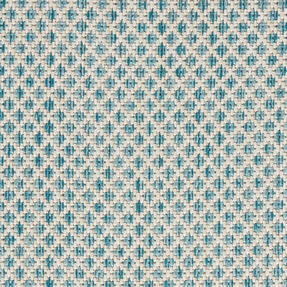 Close-up woven fabric in teal and beige with small geometric diamond pattern and textured surface.