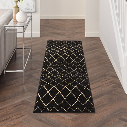 Black runner rug with beige lattice pattern on dark herringbone floor in a modern entry hallway.