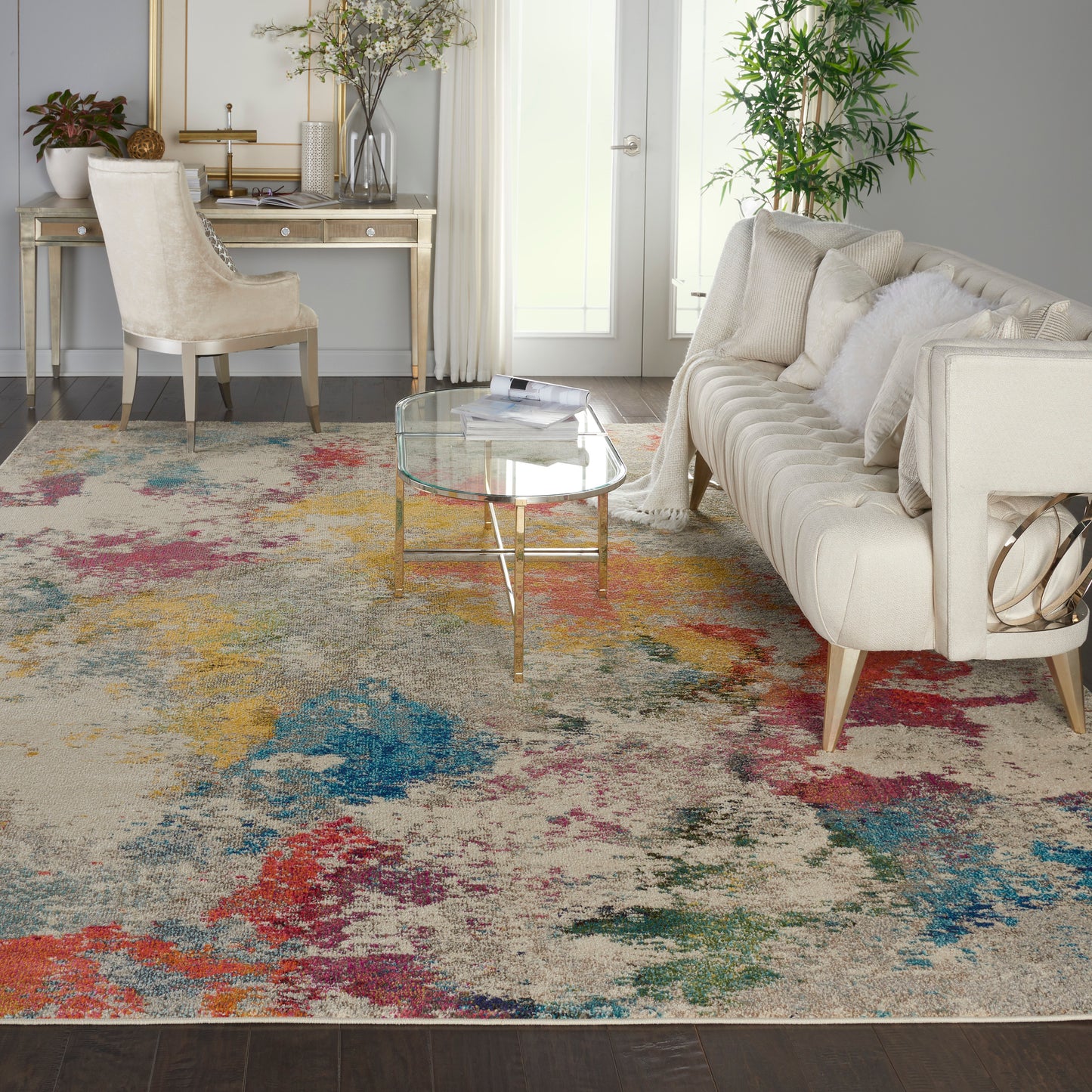 Cream tufted sofa with white cushions, glass coffee table, colorful abstract rug, gold legs, bright living room
