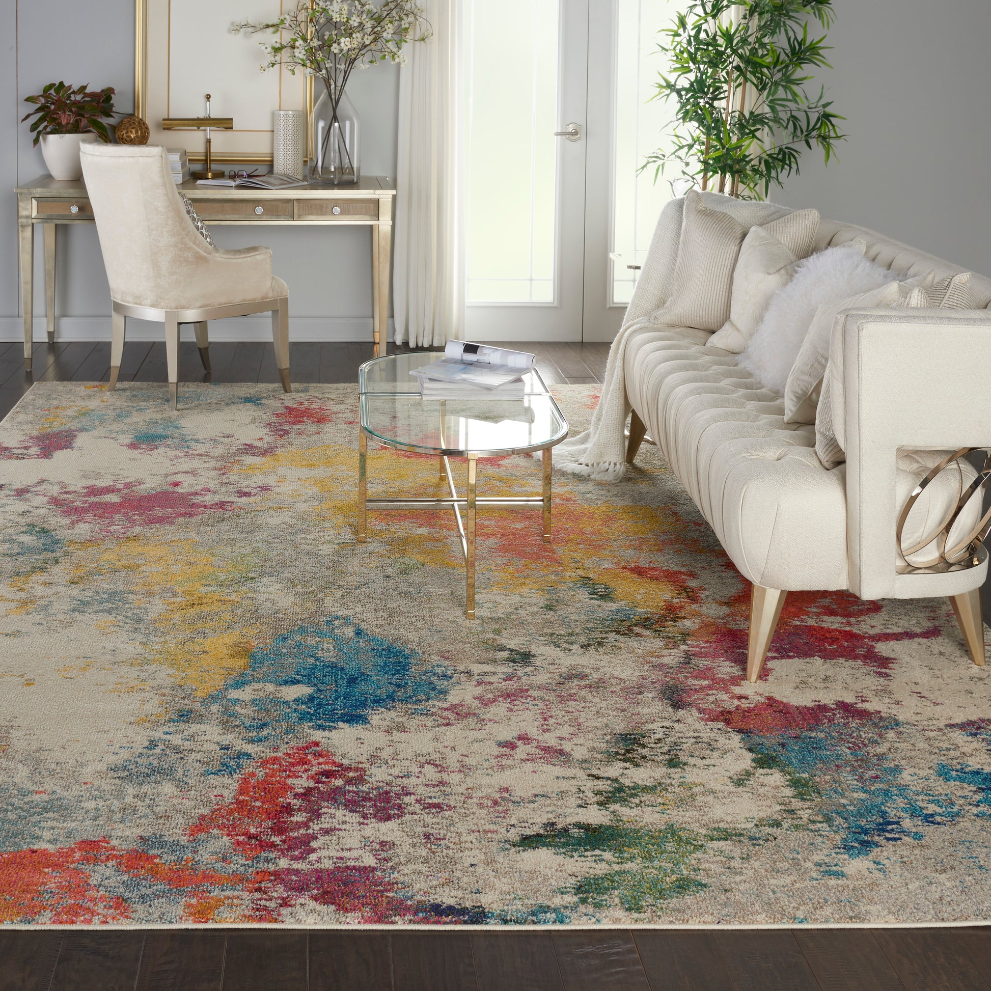 Cream tufted sofa with white cushions, glass coffee table, colorful abstract rug, gold legs, bright living room