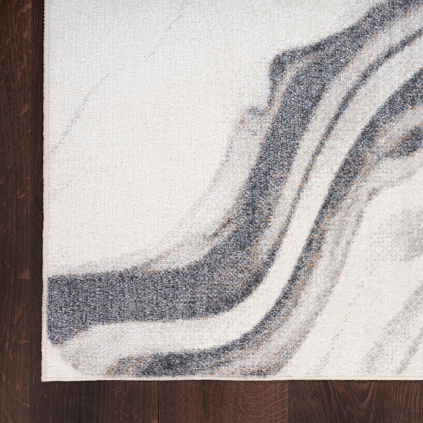 Abstract area rug with cream and gray wavy pattern and charcoal lines on a dark wooden floor.