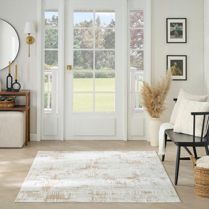 Bright living room with white French doors, beige abstract rug, neutral decor, pampas grass vase, black chair, and wall art.