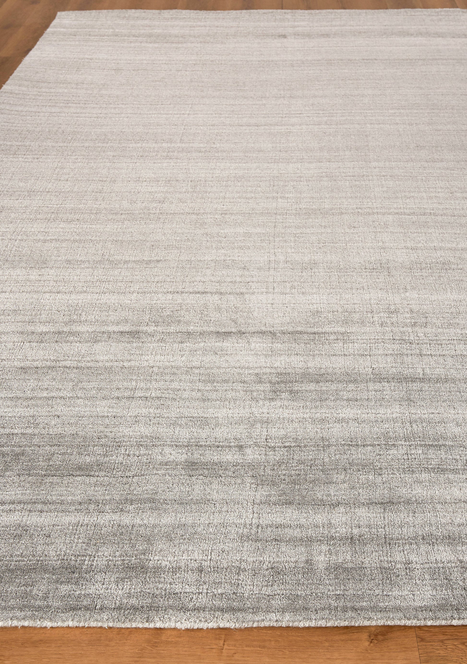 Light gray hand-loomed indoor rug, 2' x 3', with subtle tonal stripes on a hardwood floor; contemporary, versatile living room accessory.