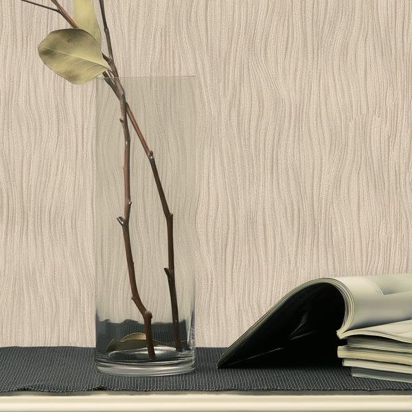 Clear glass vase with water and tall brown branches, pale green leaf, on a dark woven mat beside a curled-open magazine.