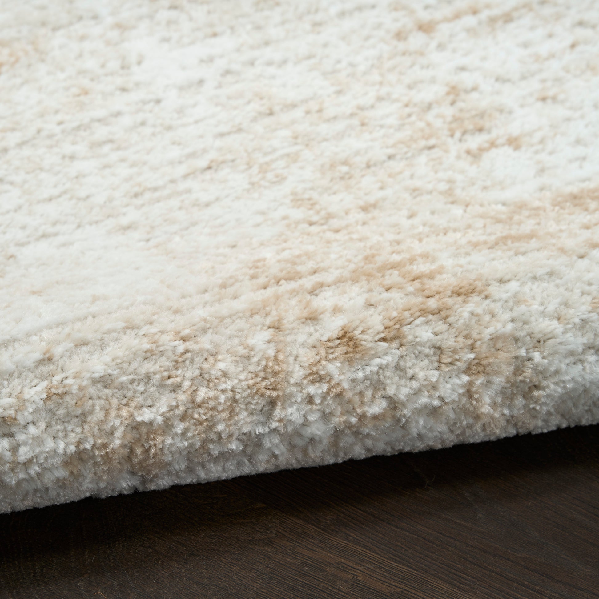 Cream beige shag rug with thick plush pile on dark wood floor.