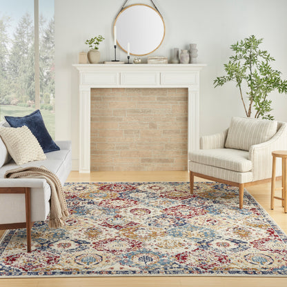 Cozy living room featuring ornate white mantel fireplace with round mirror, beige brick inset, cream armchair, neutral sofa, and a colorful oriental rug.