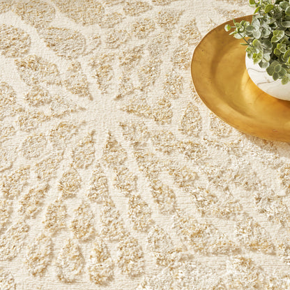 Beige textured rug with sunburst pattern; gold circular tray holding a small potted green plant.