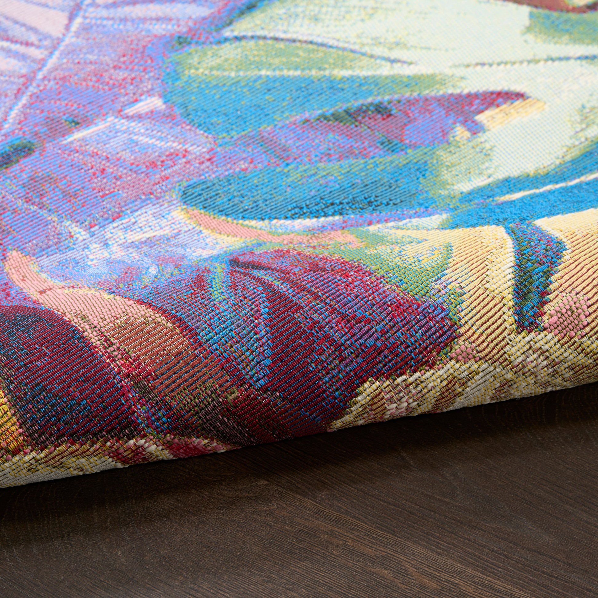 Vibrant multicolor jacquard tapestry-style pillow cover with abstract floral pattern on dark wood surface