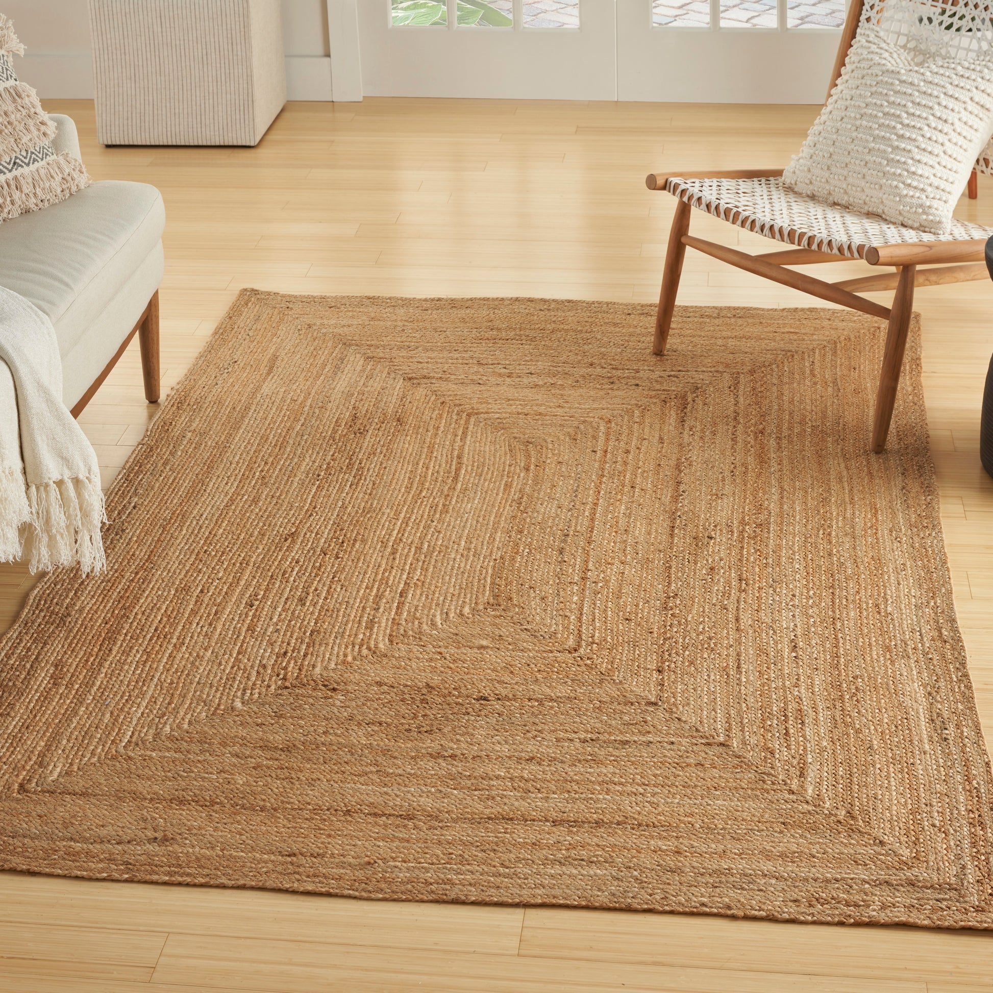 Natural jute rug with geometric concentric border; rectangular, handwoven, boho rustic living room accent.