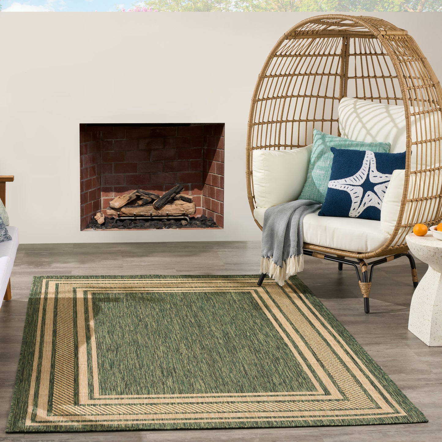 Green rug with beige border, 6' x 9', on an outdoor patio.