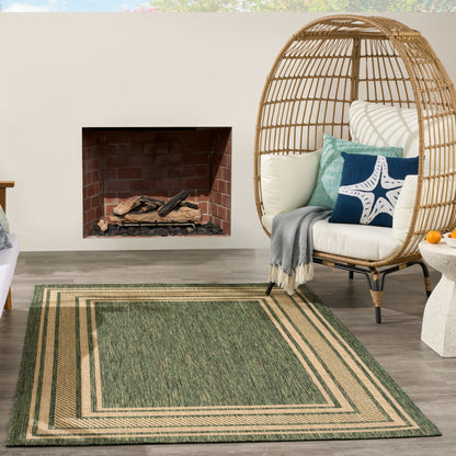 Green rug with beige border, 6' x 9', on an outdoor patio.