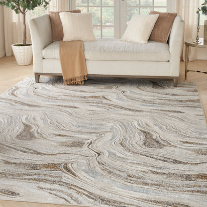 Abstract marbled area rug in gray, cream and taupe tones under a light beige sofa with cream and brown pillows and tan throw.
