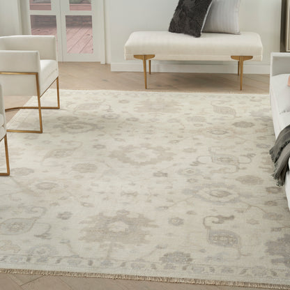 Cream rug with a subtle gray medallion pattern in a modern living room with white seating and gold legs.