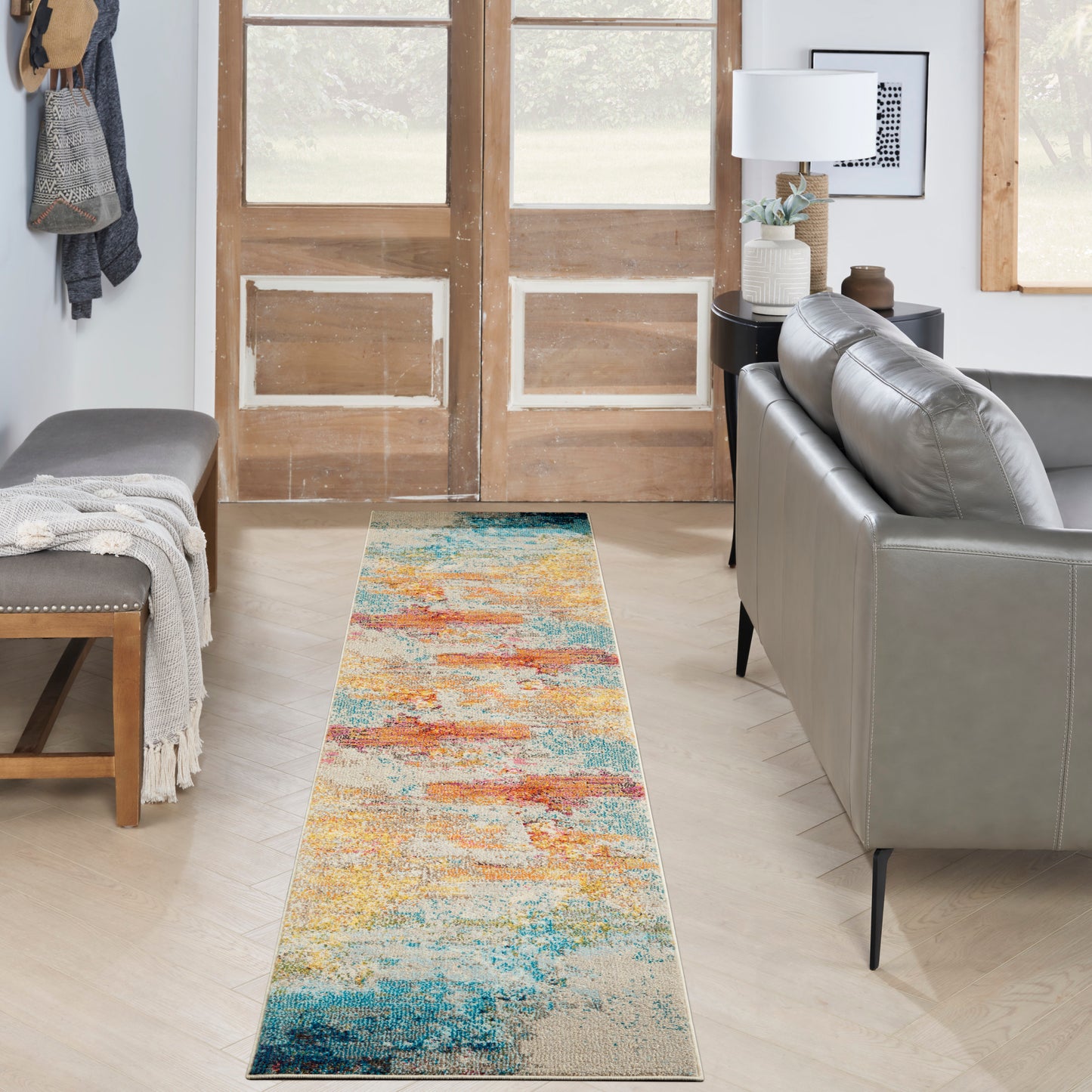 Abstract colorful runner rug with blues, teals, oranges and yellows on light wood floor in a modern living room.