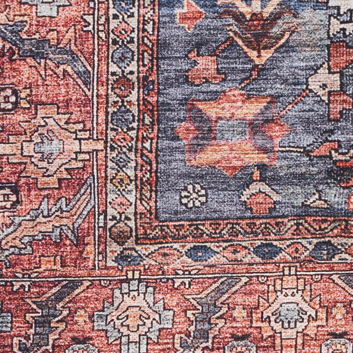 Close-up of an oriental rug with red and blue tones, ivory accents, geometric floral medallions and ornate border.