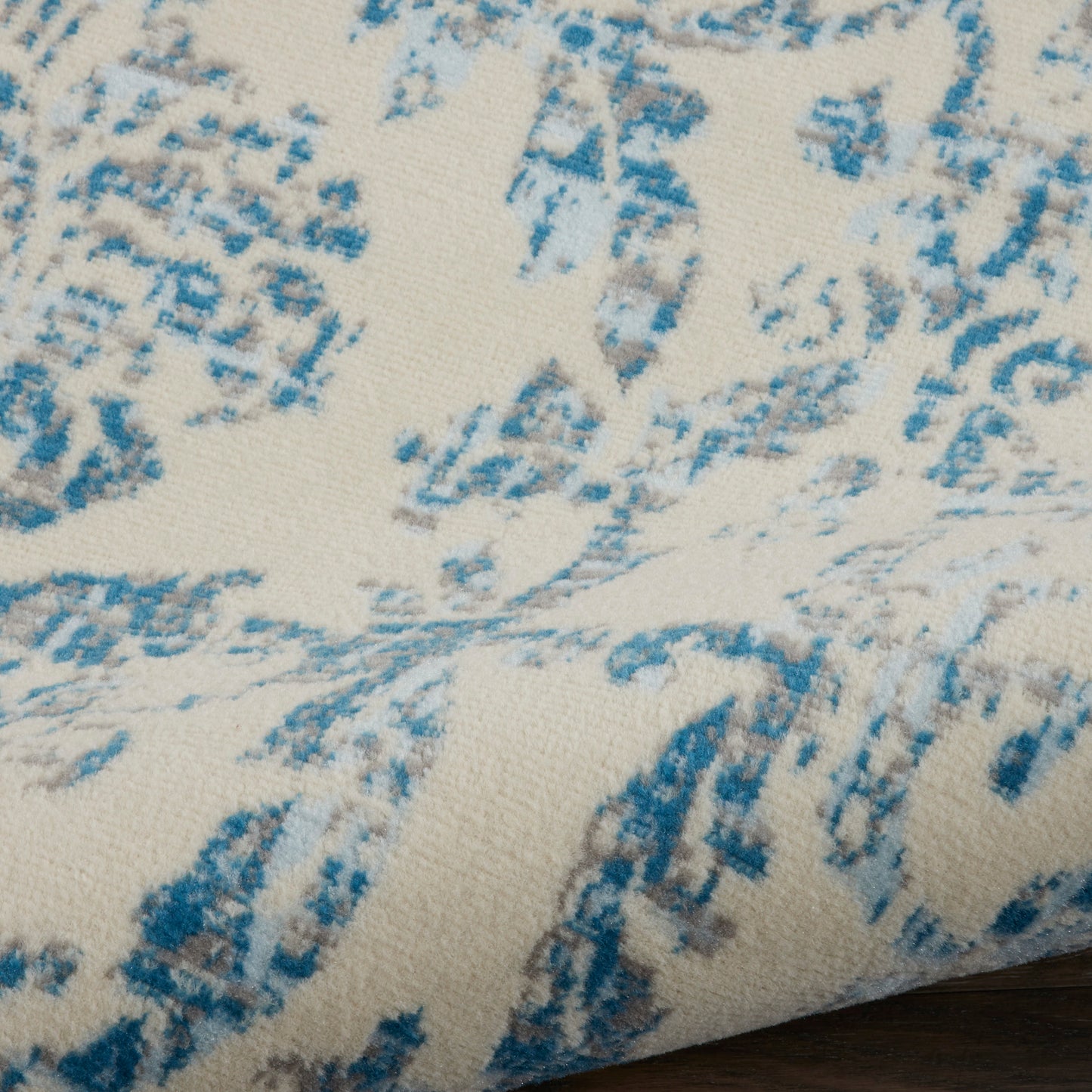 Cream rug with a blue abstract brushstroke pattern; soft woven texture, 9' x 12'.