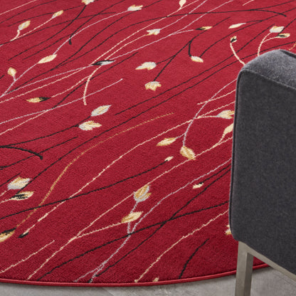 Red circular rug with cream leaf accents and black linear streaks, paired with a gray upholstered chair.