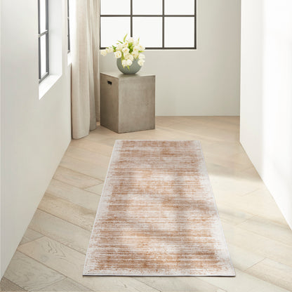 Modern minimalist hallway with light wood floor, beige-pink distressed rug runner, white walls, and a concrete pedestal topped with white flowers.