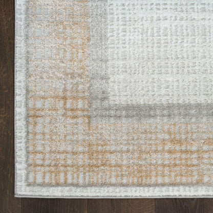 Light gray and beige patchwork area rug with geometric plaid pattern on dark wood floor, folded corner.