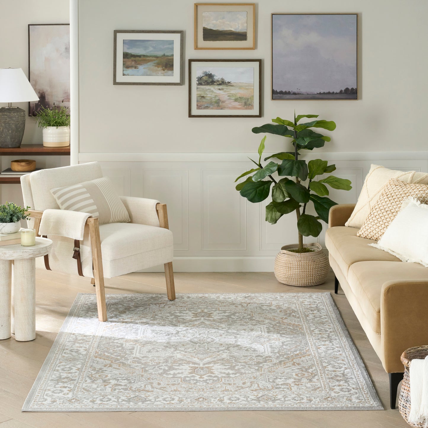 Neutral living room featuring a light patterned rug (4' x 6') with a beige armchair, tan sofa, framed landscapes, and a large plant in a woven basket.