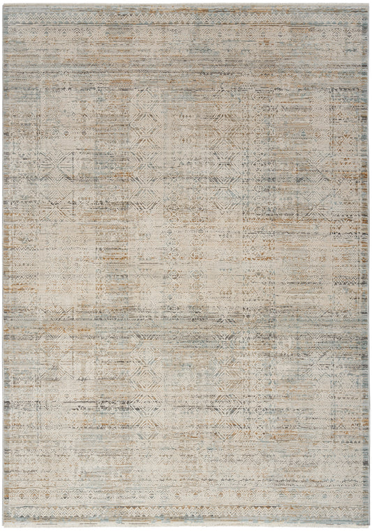 Distressed patchwork area rug with muted geometric motifs in beige, ivory, gray and pale blue.
