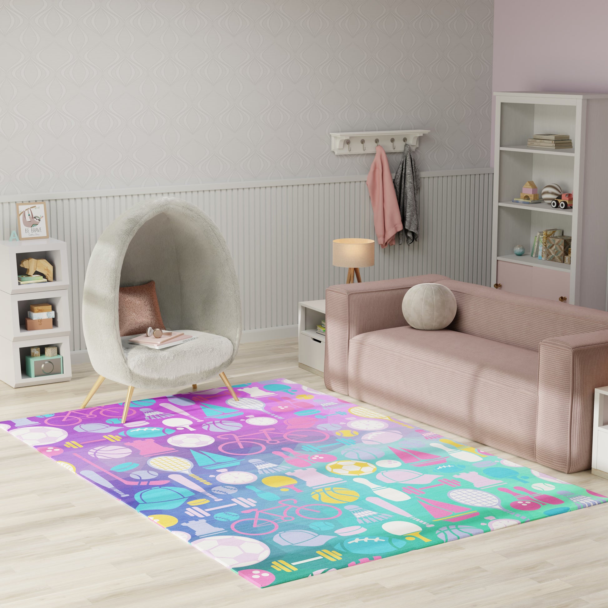 Pastel kids’ living room with pink fabric sofa, round grey pod chair on wooden legs, white shelving, and a rainbow sports-themed rug.