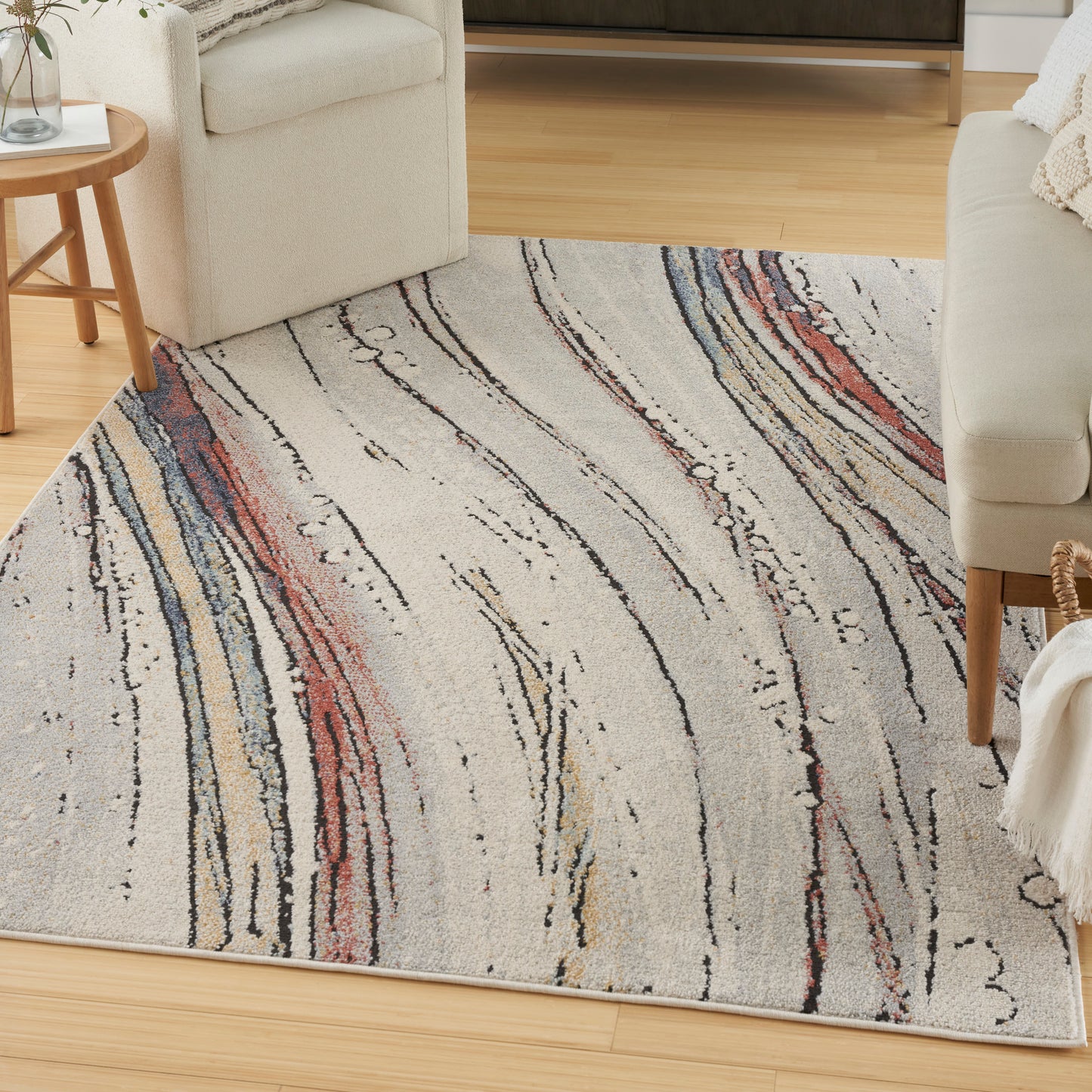 Rectangular cream rug with abstract multicolor wavy lines in red, blue, beige and black on a light wood floor.