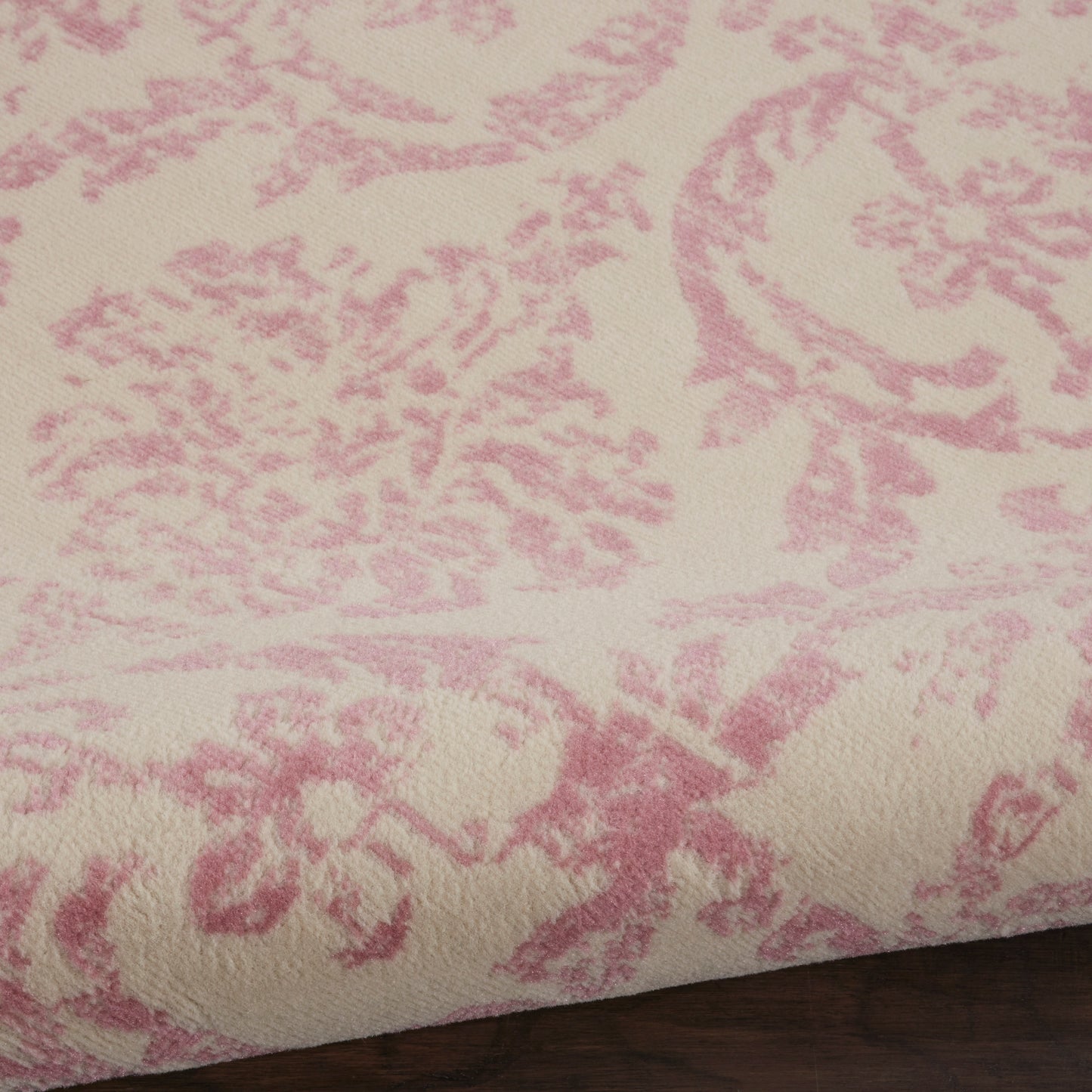 Cream round rug with pink damask floral pattern; plush velvet-like texture.