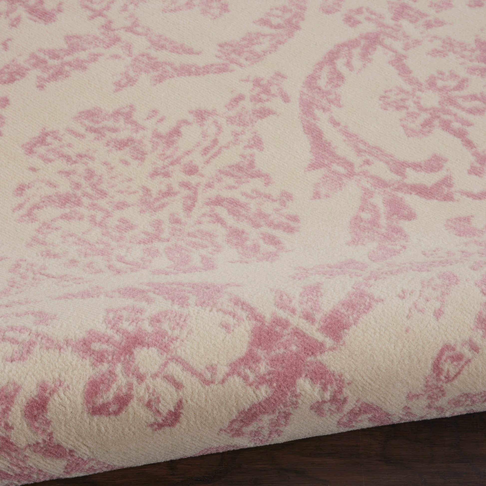 Cream round rug with pink damask floral pattern; plush velvet-like texture.