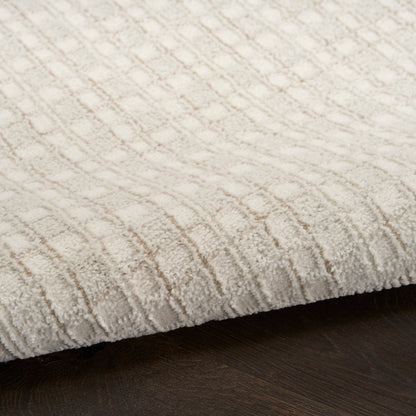 Cream beige textured area rug with a raised geometric grid pattern on dark wood floor.