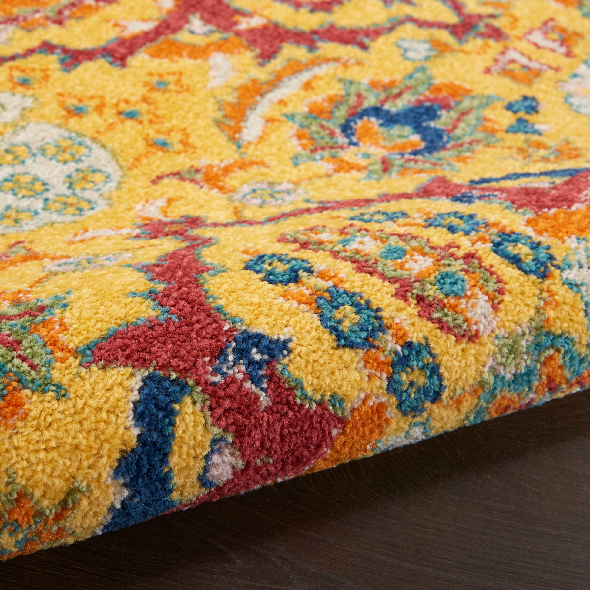 Thick shag rug in bright yellow with red, blue and teal floral patterns; plush decorative floor covering.