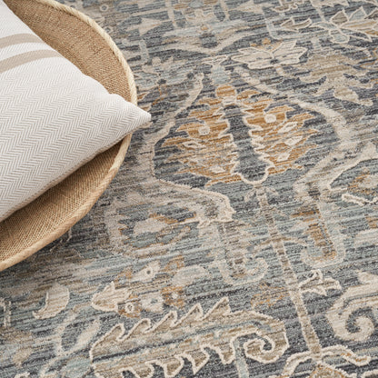 Beige herringbone pillow in a round woven basket on a blue-gray and tan oriental rug.