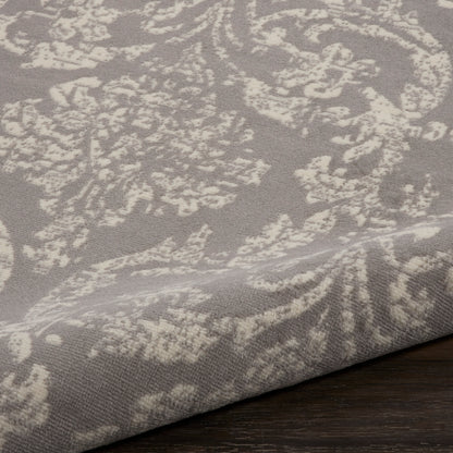 Taupe jacquard fabric with ivory damask pattern, textured weave, draped over a dark wood surface.