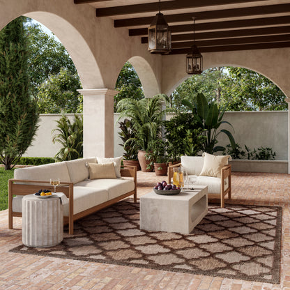 Outdoor seating under arched veranda with cream cushions, wooden sofas, concrete coffee table, and potted plants.