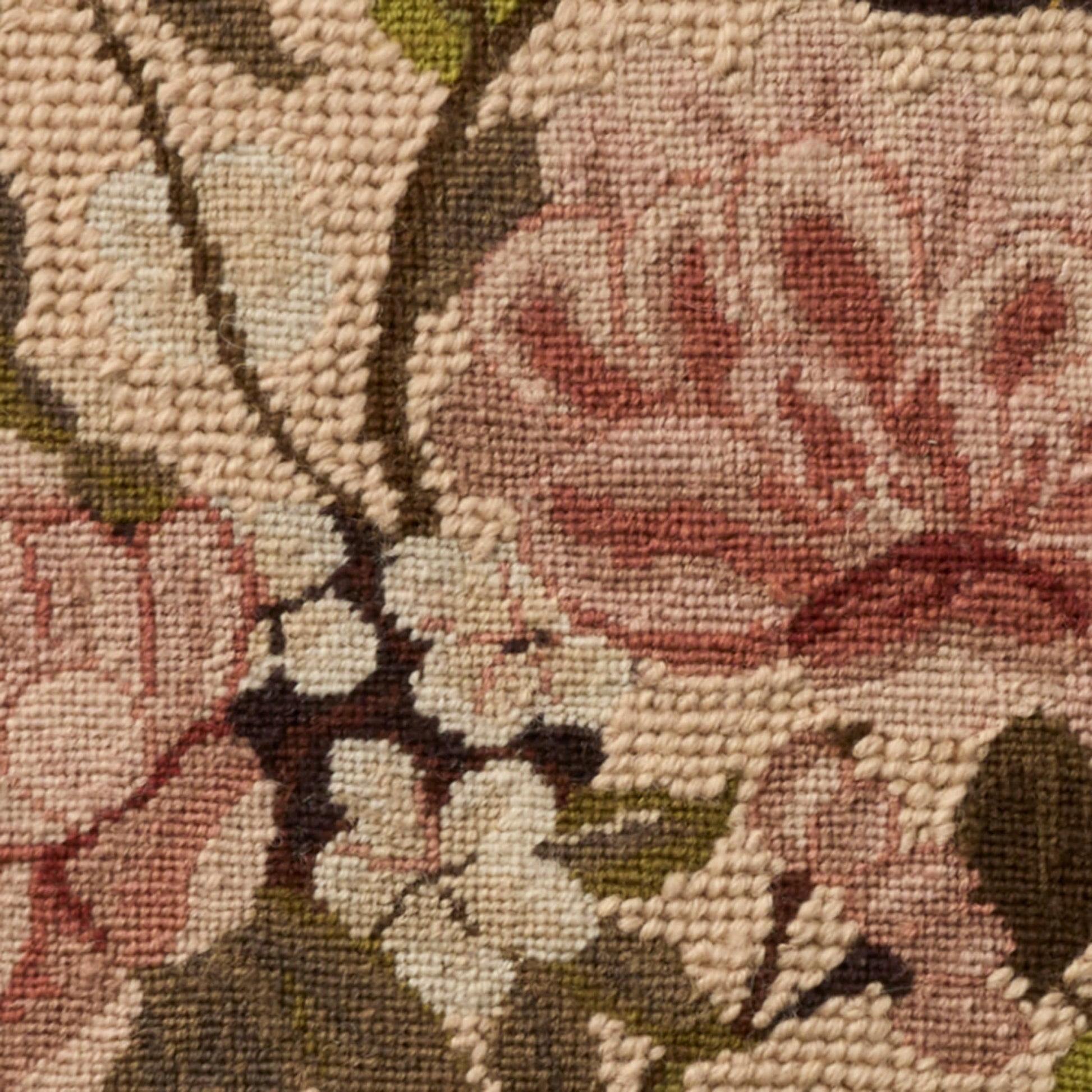 Close-up of a floral tapestry rug with pink blooms, cream petals, brown stems and olive leaves in a textured weave.