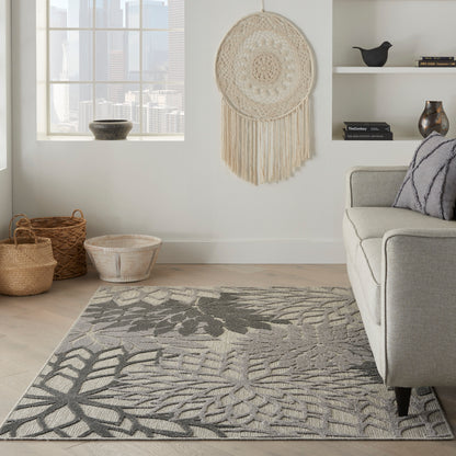 Boho living room with gray leaf-pattern rug, neutral sofa, woven baskets, and a large macrame wall hanging.