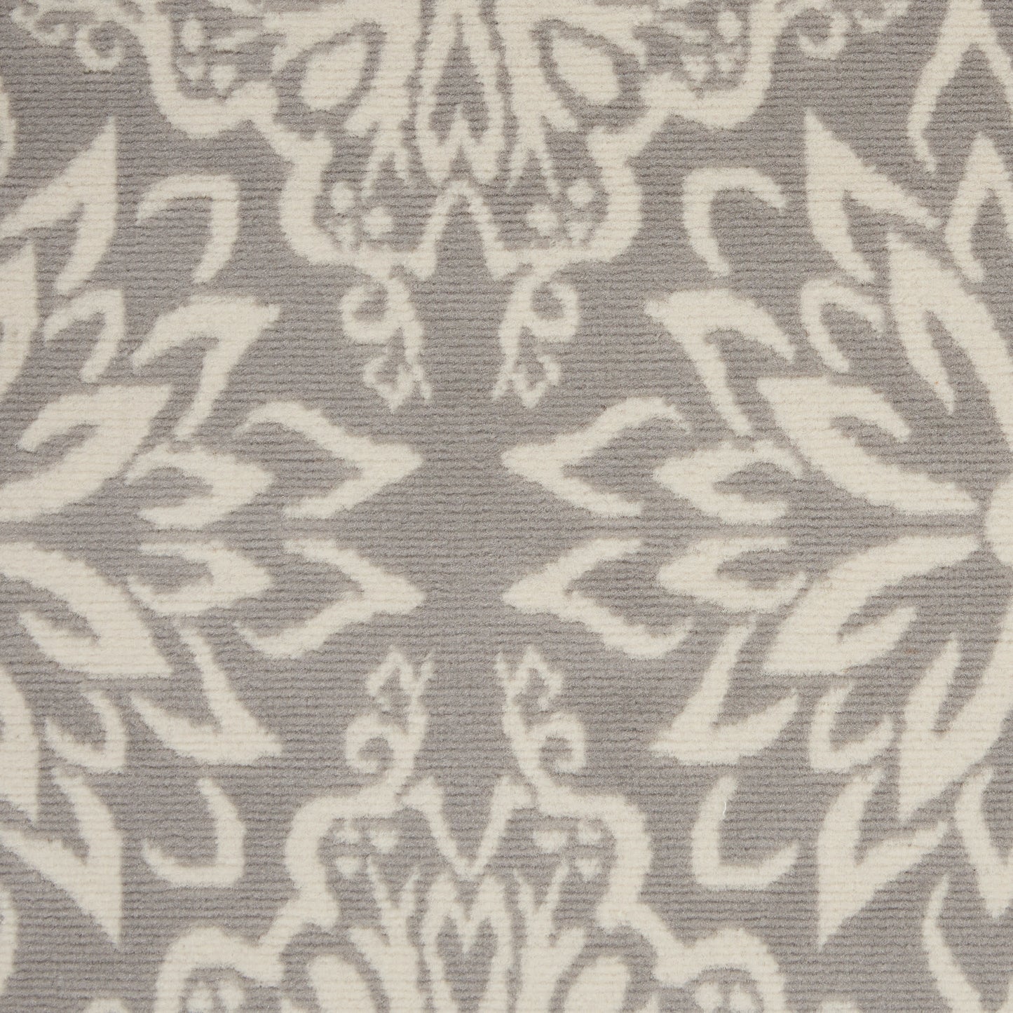 Close-up of taupe rug with ivory damask floral pattern and woven texture.