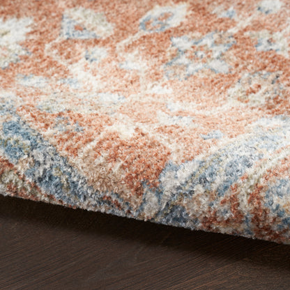Soft, high-pile area rug in peach, blue and cream with an abstract floral pattern on dark wood floor.