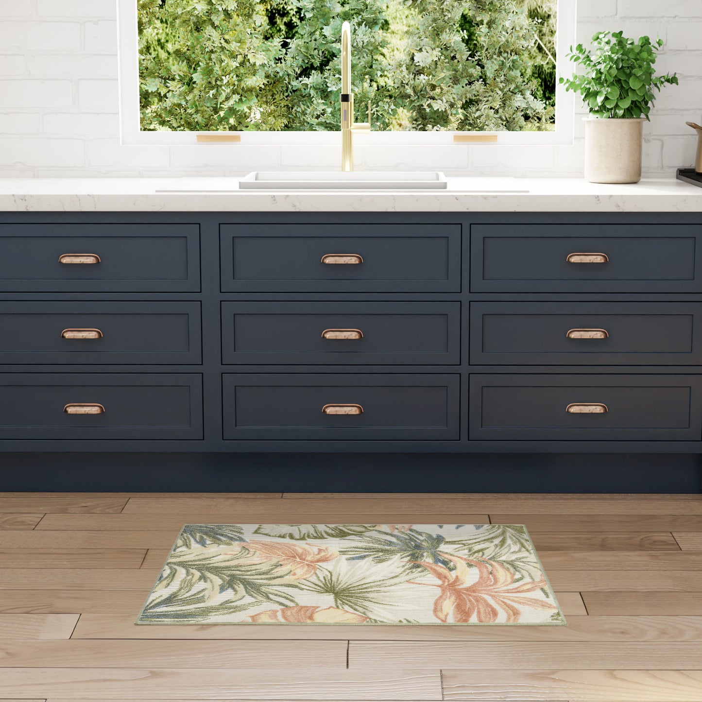 Navy blue shaker cabinets with copper handles, white marble counter, brass faucet, tropical rug on wood floor.