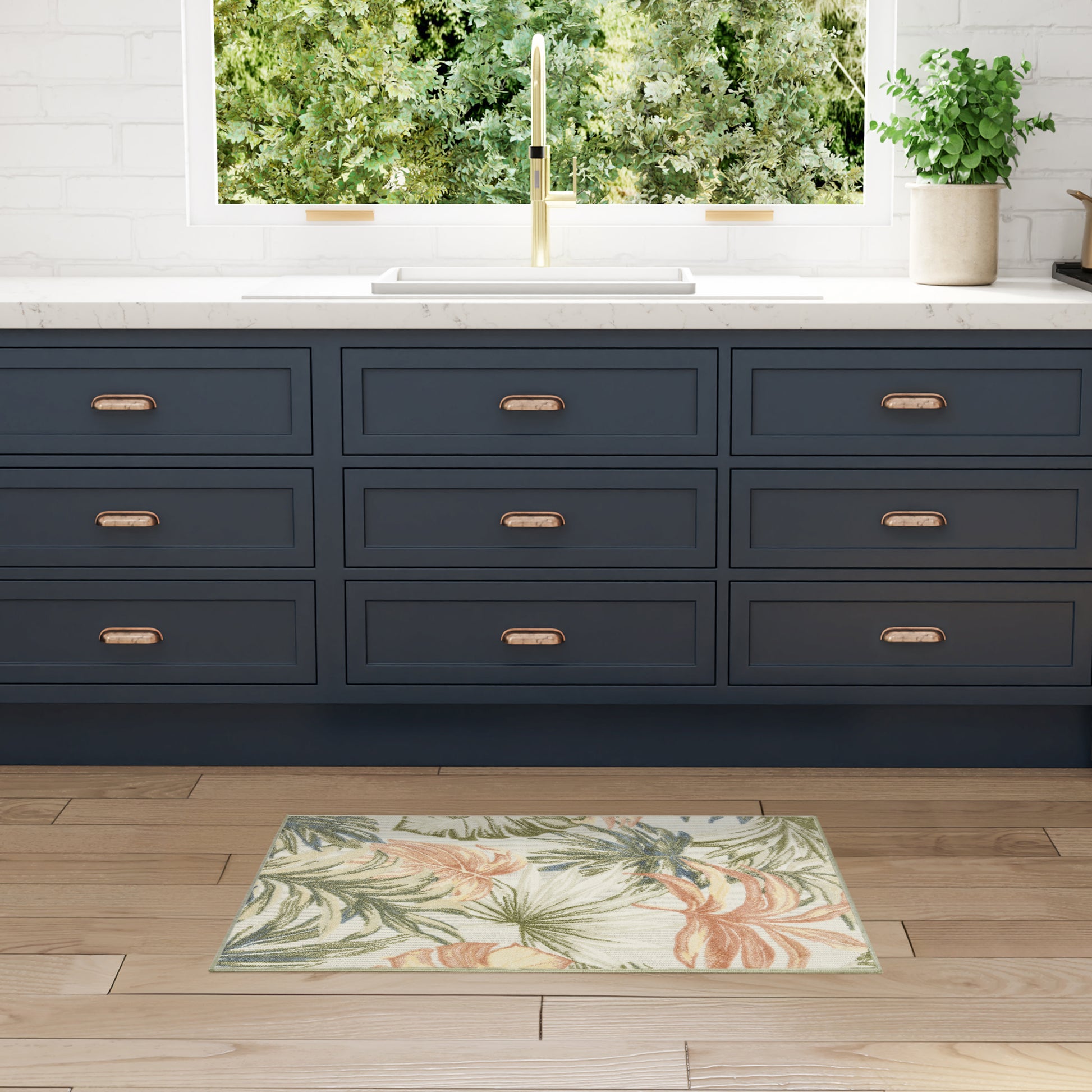 Navy blue shaker cabinets with copper handles, white marble counter, brass faucet, tropical rug on wood floor.