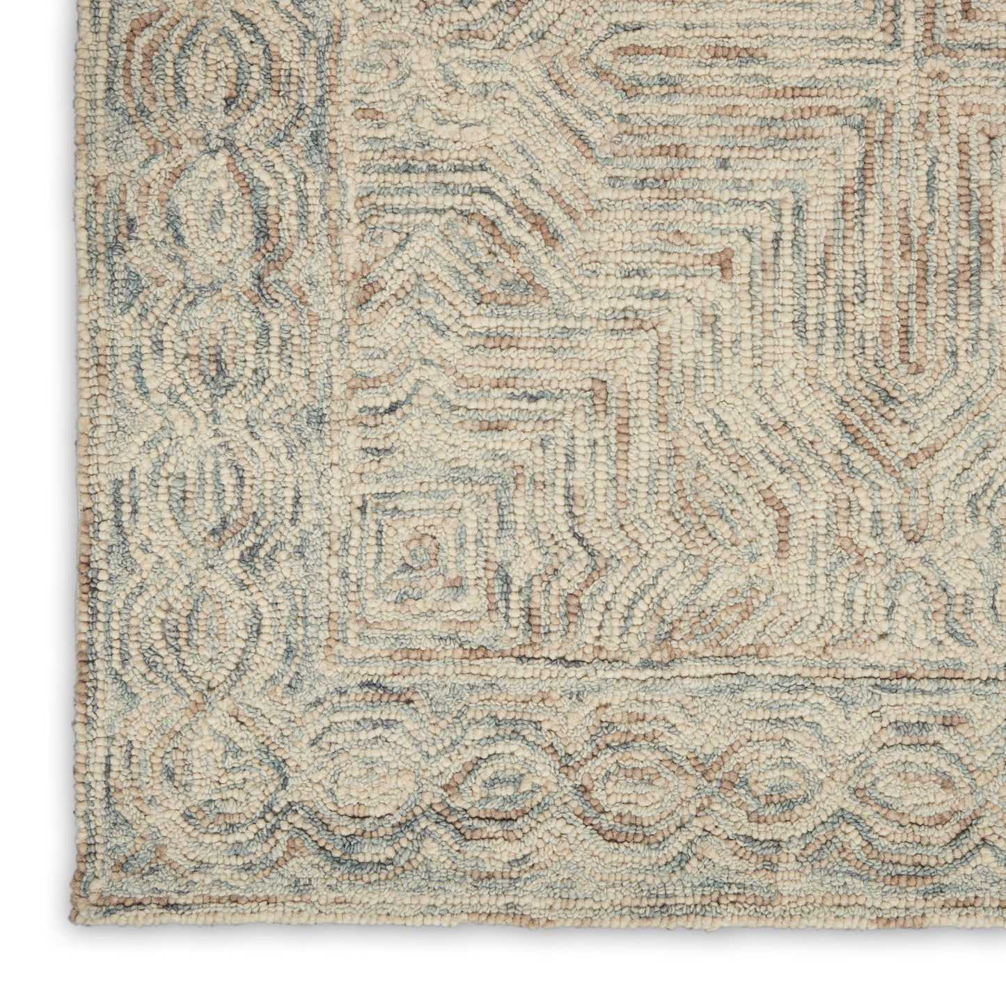 Corner of a soft textured rug in cream, blue-gray and taupe with a geometric maze center and decorative looped border.