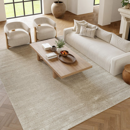 Bright modern living room with beige sofa, two cream wood-framed armchairs, a low wooden coffee table on a neutral rug.