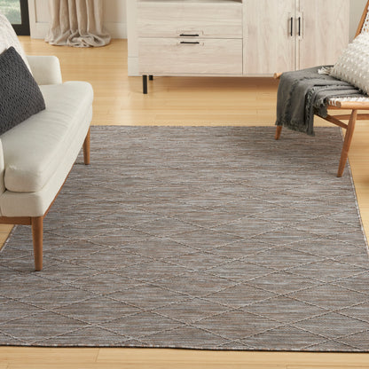 Large neutral-toned woven area rug with gray and taupe diamond lattice pattern in a modern living room.
