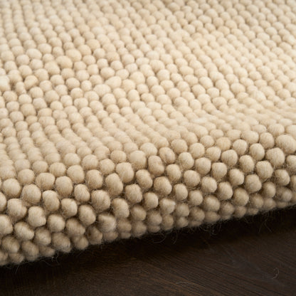Cream boucle rug with dense, round tufted bobbles on dark wood floor.