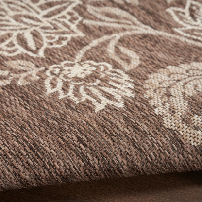 Brown woven rug with cream floral pattern, textured pile and folded edge.