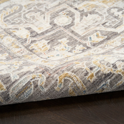Close-up of a grey and ivory oriental rug with gold accents and a distressed vintage pattern on dark wood floor.