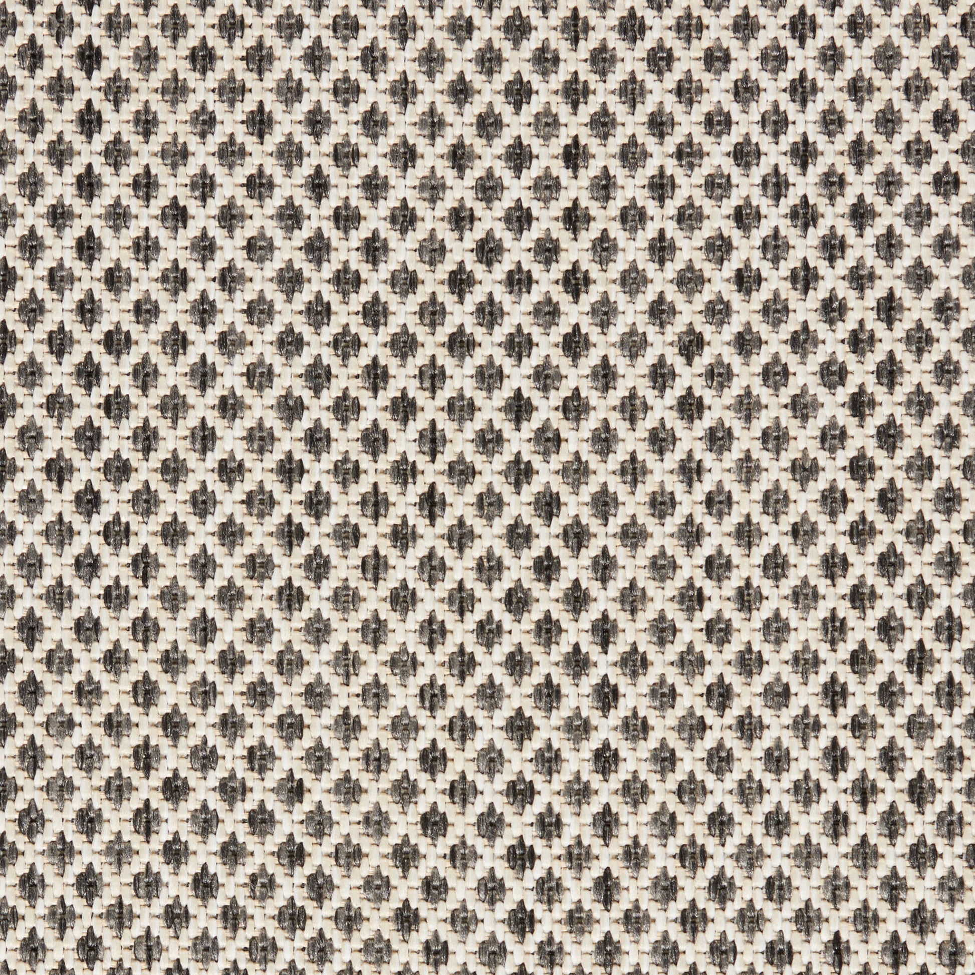 Beige woven upholstery fabric with a tiny dark geometric floral motif repeating across.