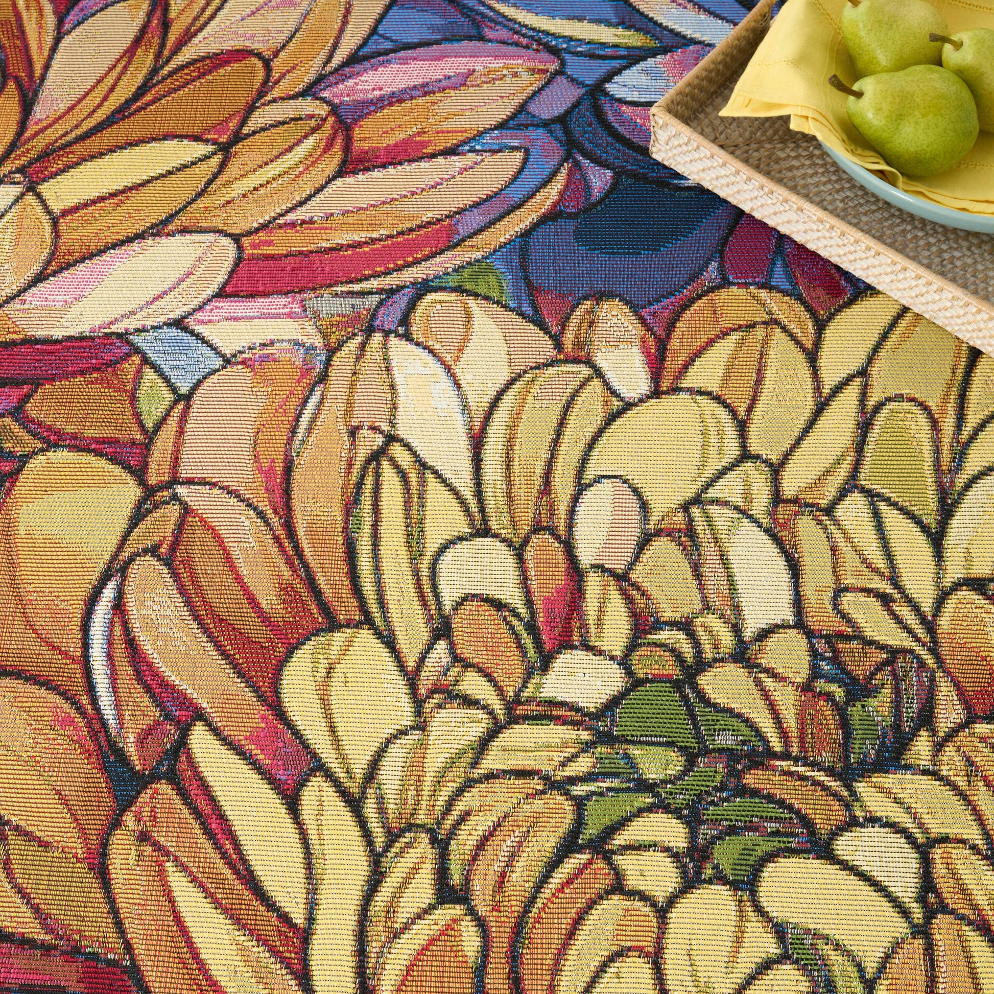 Vibrant abstract floral rug in yellows, oranges and pinks plus a woven tray with green pears on a yellow napkin.